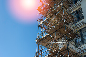 Scaffolding on multi storey building exterior during facade renovation. Bright sunny day.