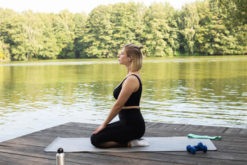 Woman doing exercises in nature near the lake. woman practicing yoga. The girl is engaged in...