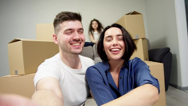 Happy family enjoying moving into a new, first purchased home, boxes with things nearby. Bank loan, affordable home for a young family