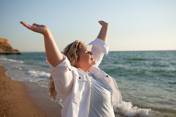 Plus size woman walking in the beach. The overweight woman raised her hands up and enjoy the sea breeze. Happy moment