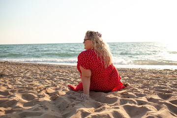 Back view of plus size woman sit in the beach. The overweight woman dressed red dress. Happy moment
