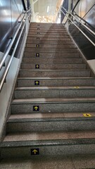 Staircase in a modern shopping mall with yellow arrow sign.