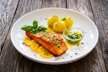 Seared salmon steak with boiled potatoes and lemon served on wooden table
