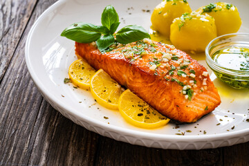 Seared salmon steak with boiled potatoes and lemon served on wooden table
