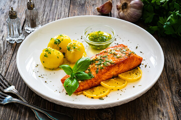 Seared salmon steak with boiled potatoes and lemon served on wooden table

