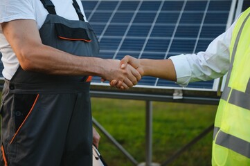 Close up businessman and engineers shaking hands after discussing install solar panels on houses under construction,Renewable energy for residential