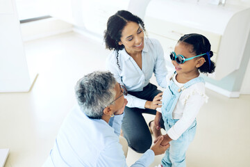Fototapeta premium Optometry, glasses and optometrist with child and mother at an eye care appointment for test. Health, wellness and senior optician with young mom and girl kid patient with lenses in an optical clinic