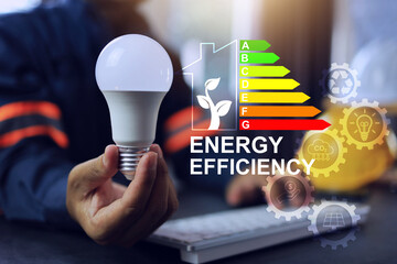 Engineer hand holding light bulb to encourage electric power save by energy efficiency label rating in modern house or home energy saving. CO2 emission reduction activity ESG market strategy.