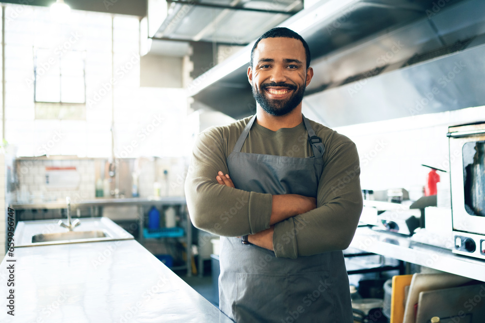 Wall mural Happy man, chef and small business owner in kitchen at restaurant for hospitality service, cooking or food. Portrait of male person, employee or waiter smile in confidence for professional culinary