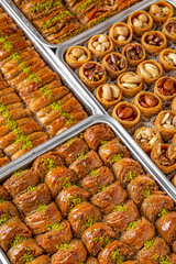Different types of freshly baked baklava in baking trays. Turkish desert with peanut, pistachio for holiday or ramadan. Traditional Middle Eastern Flavors. Selective focus, pattern.