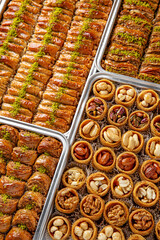 Different types of freshly baked baklava in baking trays. Turkish desert with peanut, pistachio for holiday or ramadan. Traditional Middle Eastern Flavors. Selective focus, pattern.