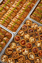 Different types of freshly baked baklava in baking trays. Turkish desert with peanut, pistachio for holiday or ramadan. Traditional Middle Eastern Flavors. Selective focus, pattern.