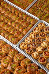 Different types of freshly baked baklava in baking trays. Turkish desert with peanut, pistachio for holiday or ramadan. Traditional Middle Eastern Flavors. Selective focus, pattern.