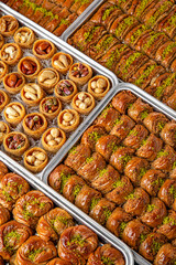 Different types of freshly baked baklava in baking trays. Turkish desert with peanut, pistachio for holiday or ramadan. Traditional Middle Eastern Flavors. Selective focus, pattern.