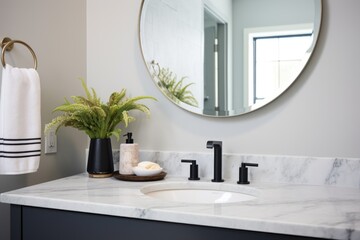 bathroom with round mirror and marble countertop