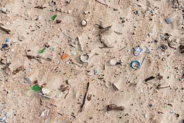 Plastic trash in sand on sea beach. Pollution by microplastic rubbish on coastline