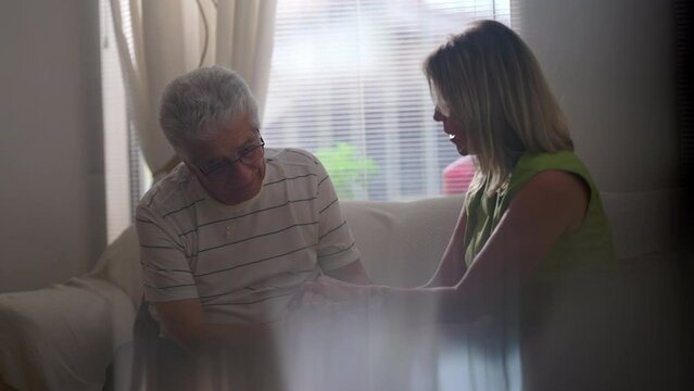 Senior Man Struggling With Difficulties Being Being Listened By Supportive Female Partner During Hard Times. Woman Active Listening An Elderly Person At Home Seated In Candid Scene