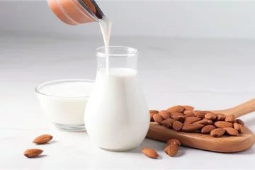 Fotobehang almond milk dripping off a wooden spoon onto a white table © altitudevisual