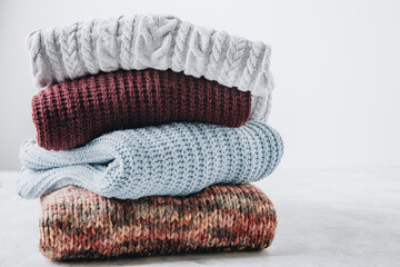 Sweaters. Multi-colored sweaters stacked on gray background.