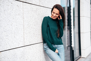 Street fashion portrait of beautiful caucasian woman walking outdoors. Beautiful young model in warm sweater. Fashion stylish pretty female posing in the street, having fun in city