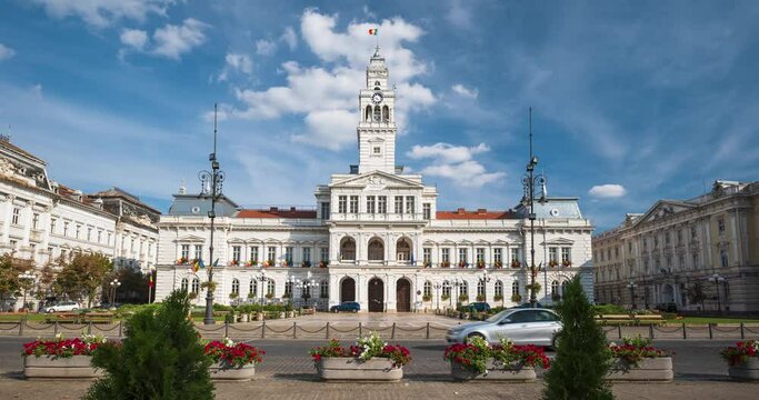 22-08-2023 Arad city, Romania. Time lapse of the city hall from across the street. Low angle view of passing traffic and pedestrians, sunny summer day, passing clouds, wide angle