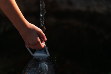 taking water into a bottle from a forest spring