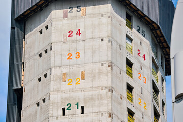Tall modern skyscraper construction, concrete walls with numbers marking floors to be built