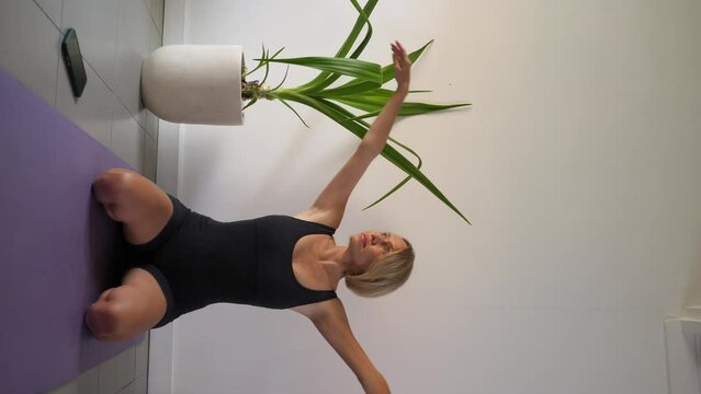 Young caucasian woman doing yoga in white studio using mobile phone in afternoon