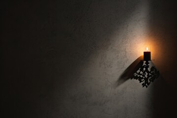 Candle flame with shadows on a textured wall. Generative AI