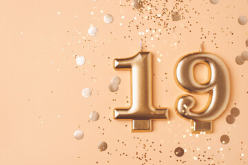 Gold candles in the form of number nineteen on peach background with confetti. 19 years celebration. Greeting banner.