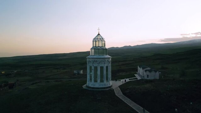 Church of the Holy Angels and Eternity Park in Armenia at sunset. In the background of the high mountain Ararat in clear weather. Drone video. The camera moves in an arc around the object.