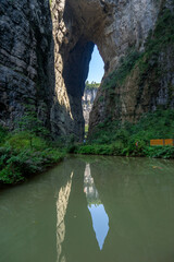 The water reflection of Qinglong Bridge in Wulong Karst, Chongqing, China, presents a serene and picturesque scene.