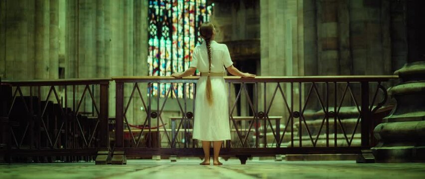 Barefoot woman wanderer looking for God in church. Adult girl with braided hair in a long dress in the Temple.
