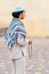 A guy of Arab appearance in national clothes with rosary in his hand prays and worships Allah in...