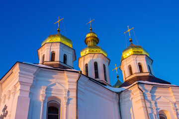 Fototapeta na wymiar golden domes of the Orthodox Church in the pink rays of the setting sun in Europe in Ukraine