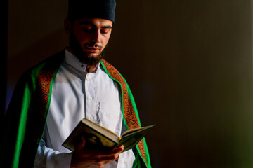 Islamic prayer concept Close-up of a Muslim man sitting on his knees praying with the Holy Quran in...