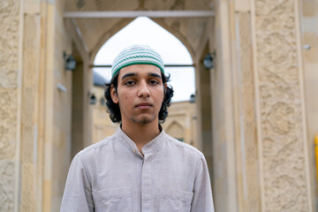 portrait of a young man of Muslim appearance leaving the mosque after prayer on terrace with...