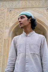 portrait of a young man of Muslim appearance leaving the mosque after prayer on terrace with...