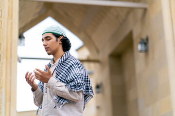 A guy of Arab appearance in national clothes with rosary around his neck prays in the courtyard of...