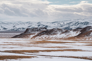 Pastel colors with the snow covered mountains in the distance. Scenic minimalist landscape with rocks in pastel tones. Snowy pasture scenery in winter. Mongolia landscapes.
