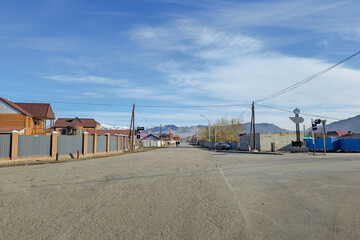 Obraz premium Northern Mongolia. City of Ulgiy. Houses of the street stretching into the distance to the mountains, Mongolian people on the street are busy with their worries.