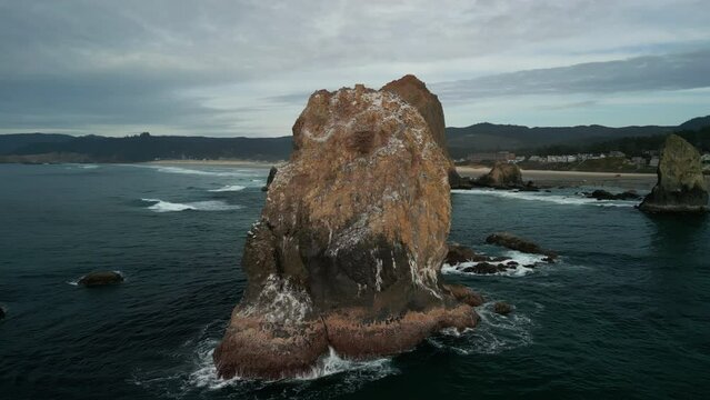Haystack Rock beach in coastal town Cannon Beach, Oregon. Wide aerial shot footage