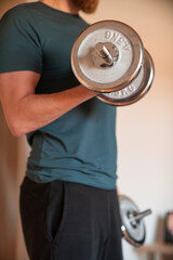 Fototapeta na wymiar Bearded man training with weights and dumbells at home to stay healthy.