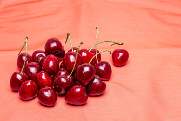 Red fresh cherries on on a red cloth background
