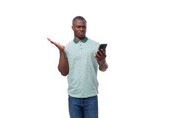 young smart american guy dressed in a mint t-shirt reads messages on a smartphone and is surprised