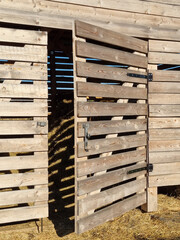 Barn made of boards for storing hay. Plank barn with an open door.