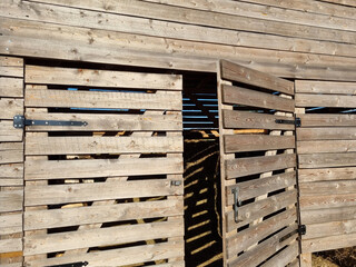 Barn made of boards for storing hay. Plank barn with an open door.