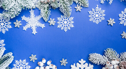 Christmas holidays composition with white christmas decorations and fir tree branches on blue background with copy space, top view