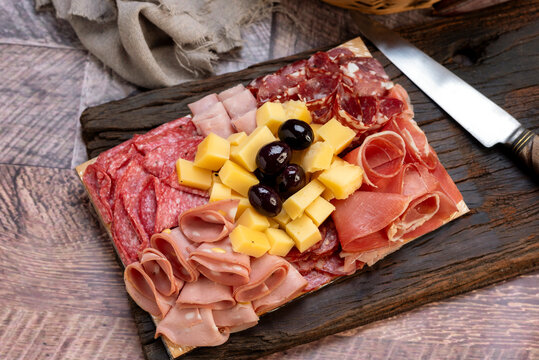 chopping board of cheeses and salami cold cuts of various varieties homemade country bread with almonds and handmade knife