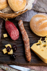 chopping board of cheeses and salami cold cuts of various varieties homemade country bread with almonds and handmade knife